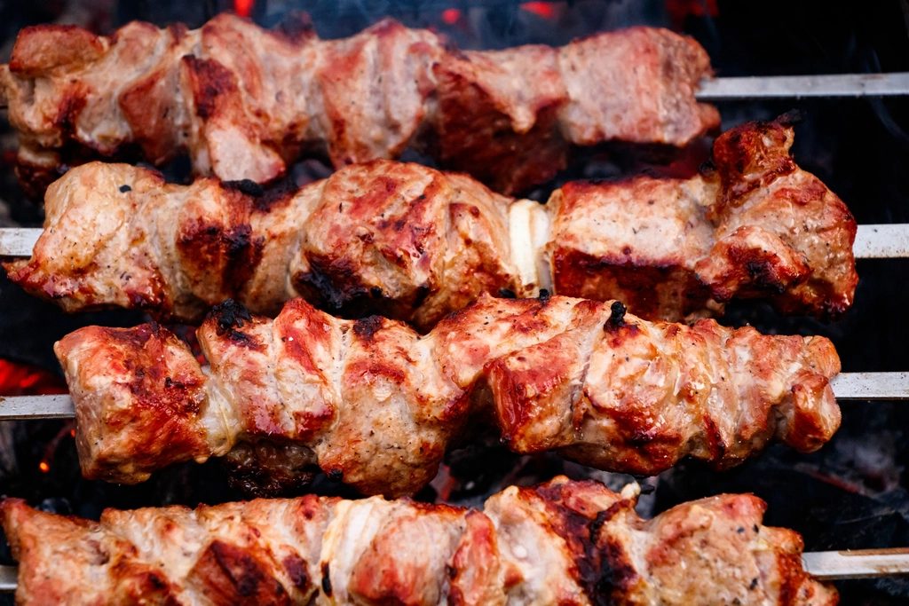 Skewers of meat cooking over coals